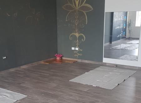Stanza tranquilla per yoga con tappetini, pareti decorate e uno specchio riflettente.